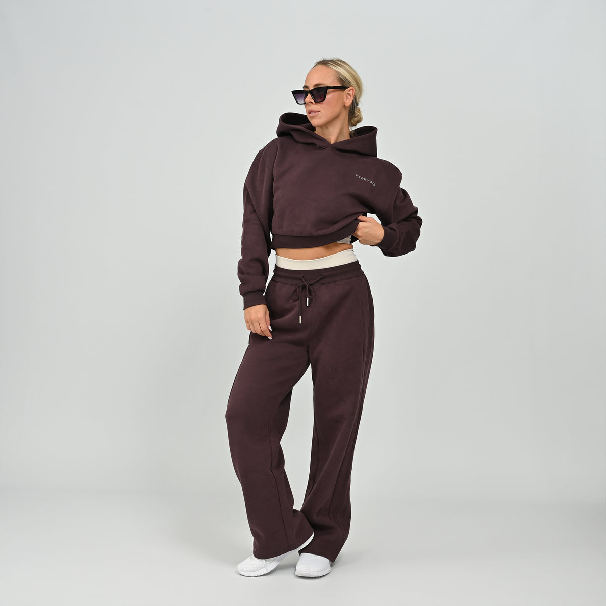 Front view of model wearing the aubergine Hybryd Barstow cropped hoodie and wide leg joggers matching lounge set