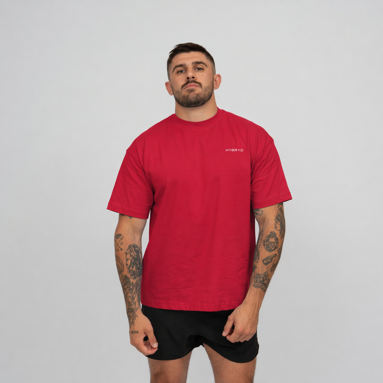 Man wearing a red t-shirt with a Hybryd logo on a grey background