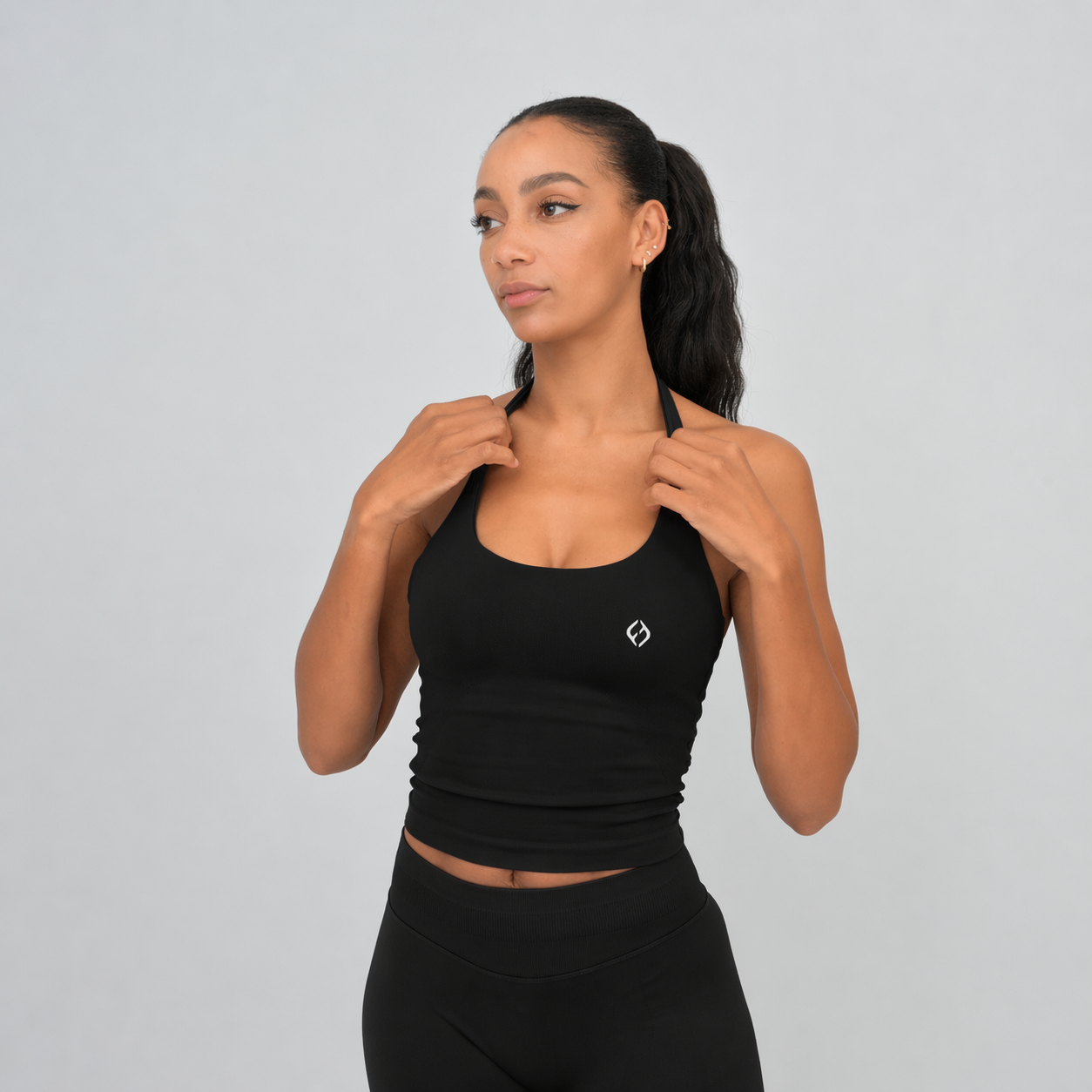 Woman wearing a Hybryd black athletic outfit with a logo on a gray background