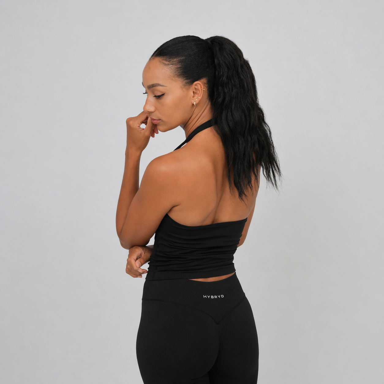 Woman wearing a black athletic Hybryd outfit on a grey background