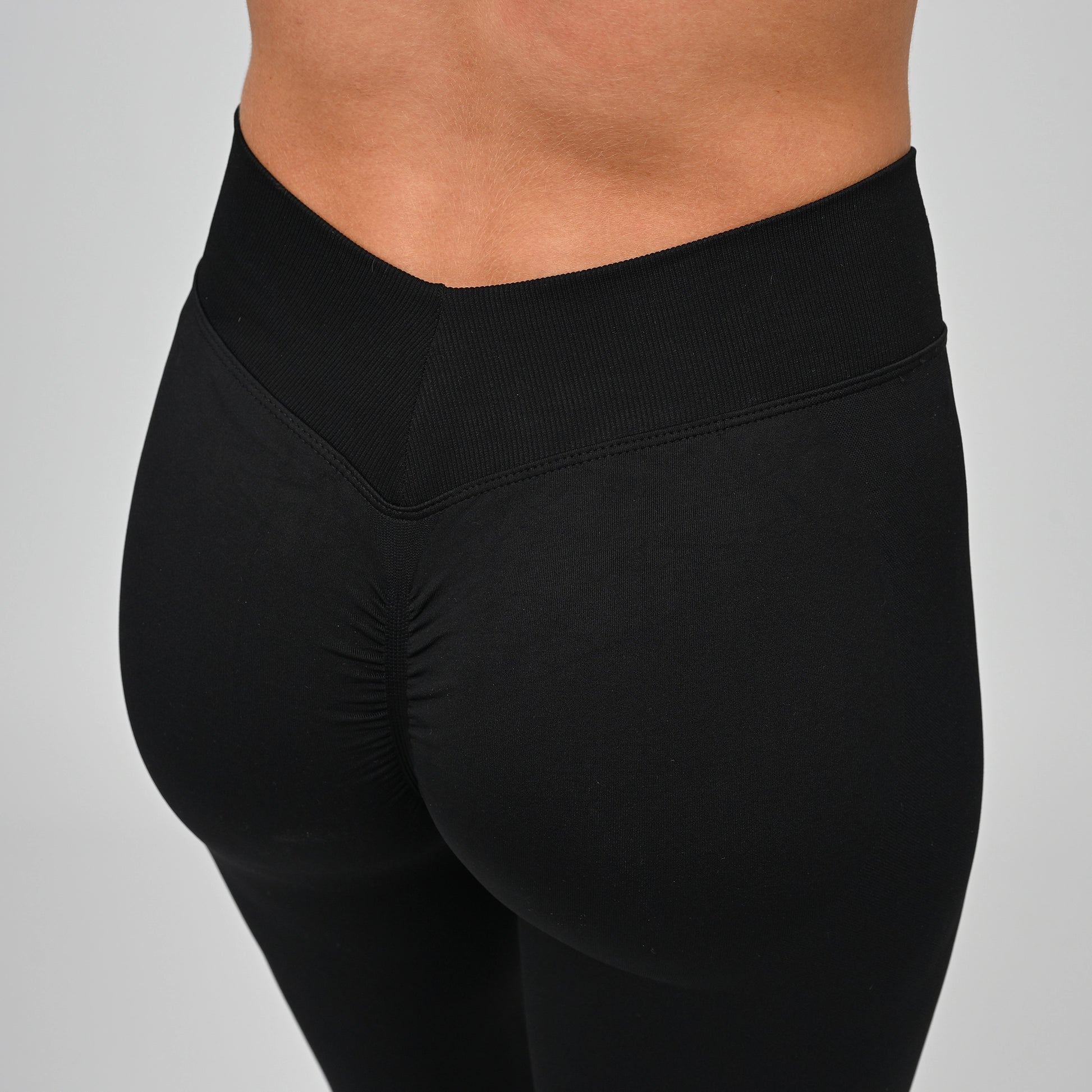 Close up shot of a girls bum wearing black Hybryd equinox leggings that have a v-dip rear waist and a scrunch bum. From activewear brand Hybryd