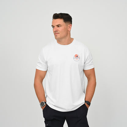Hyrox athlete wearing a white crew-neck t-shirt with a small circular Hybryd logo on the left chest, paired with dark pants, standing against a light gray studio background. From activewear brand Hybryd.