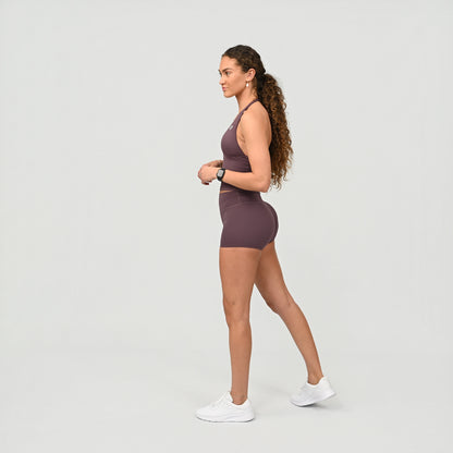 Woman wearing a mauve Hybryd sports wear athletic outfit on a light gray background
