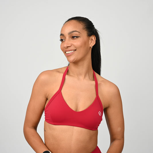 Gym girl wearing a red minimal sports bra from Hybryd. Comes with adjustable halter neck strap.