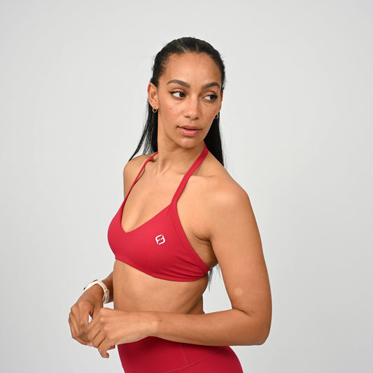 Gym girl wearing a red minimal sports bra from Hybryd. Comes with adjustable halter neck strap.