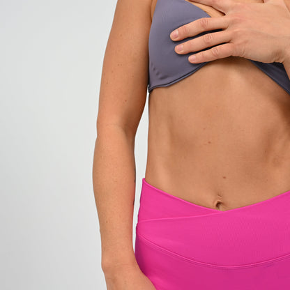 Crossfit athlete wearing a candy pink pair of booty shorts. Crossover waist and cinch bum. Contour shading  around the bum. Made by gymwear and activewear brand Hybryd