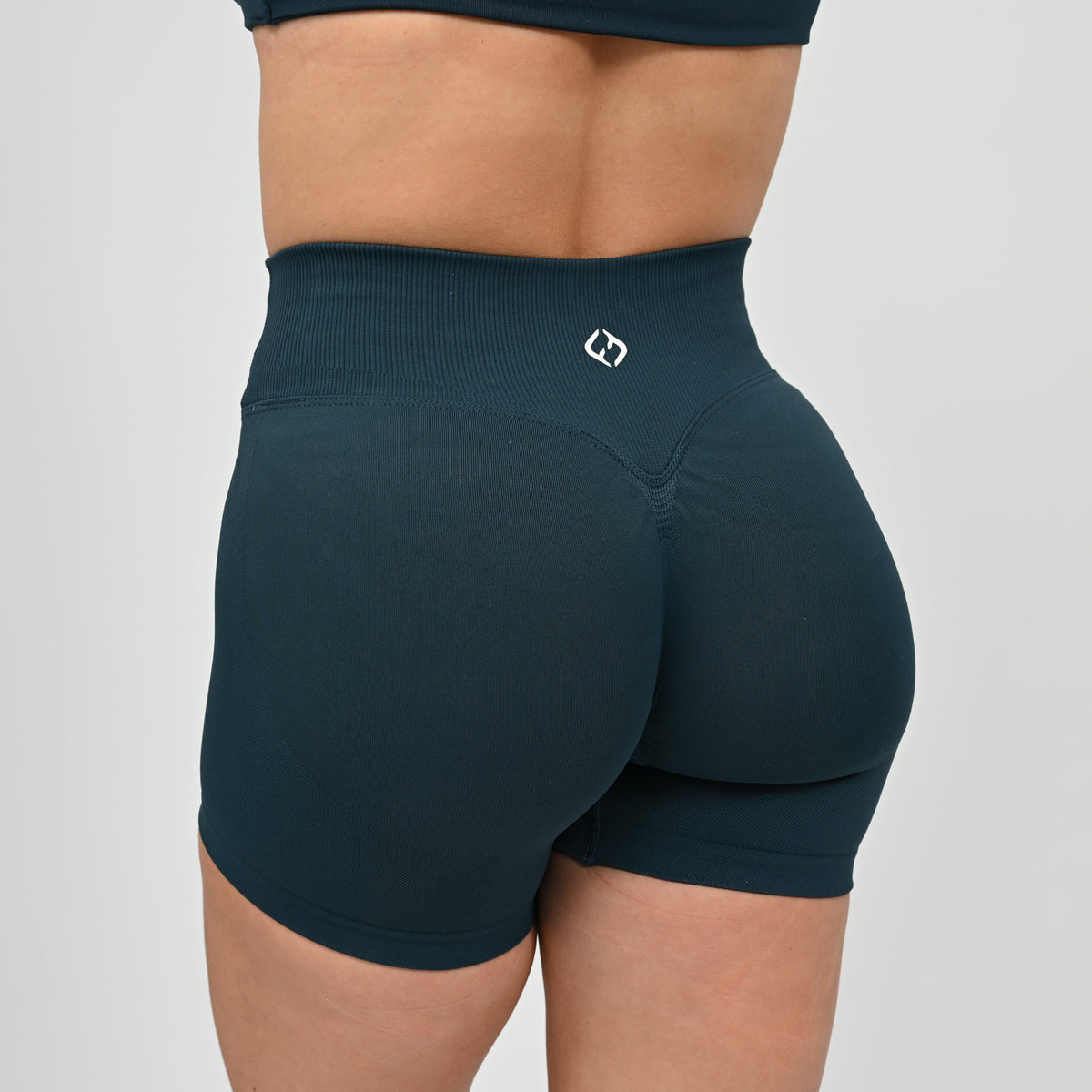 Crossfit athlete wearing a teal pair of booty. Shorts have a Crossover waist and scrunch bum. Contour shading  around the bum. Made by gymwear and activewear brand Hybryd