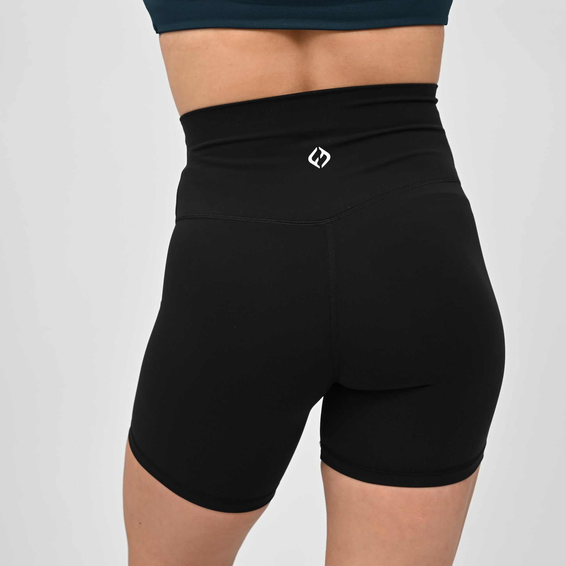 Crossfit girl wearing plain black, high waisted bootie shorts. No cinch. From activewear brand Hybryd.