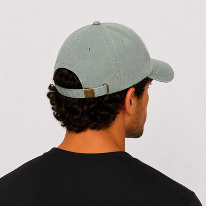 A man wearing an green/grey low profile, 6 panel design. Unstructured, Soft front, Pre-curved visor with a Metal buckle closure. From the gymwear brand Hybryd.