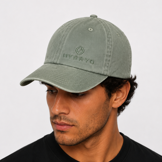 A man wearing an green/grey low profile, 6 panel design. Unstructured, Soft front, Pre-curved visor with a Metal buckle closure. From the gymwear brand Hybryd.