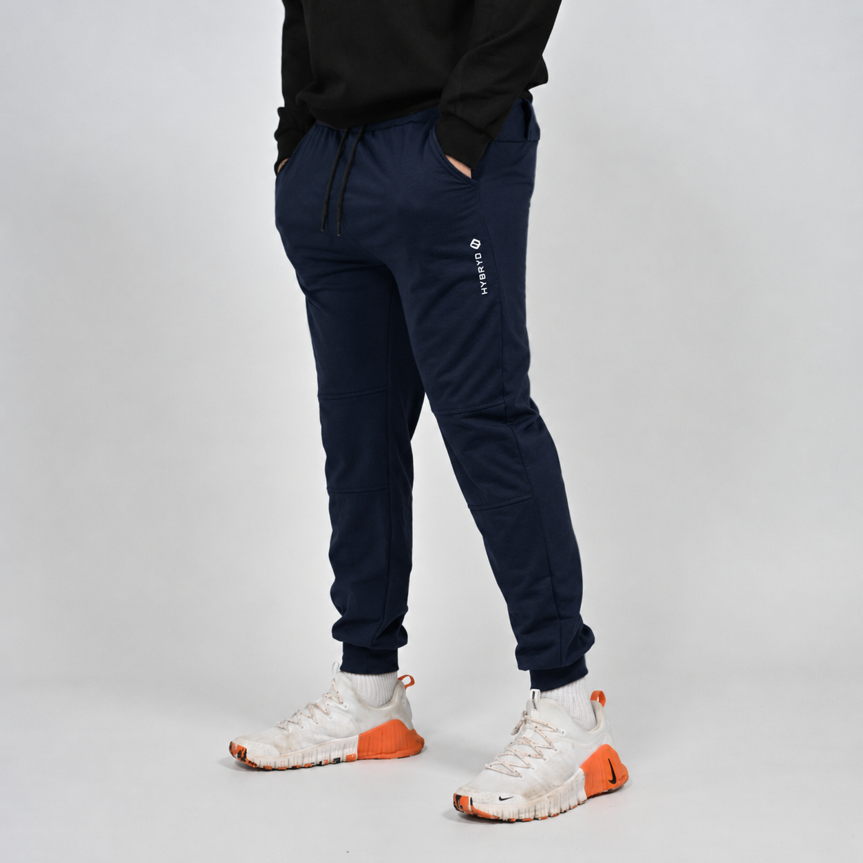 A navy slim fit jogger with Hybryd logo. Worn by a crossfit athlete with white Nike trainers. 