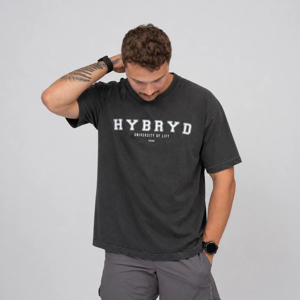 Man wearing a black t-shirt with 'HYBRYD' branding on a grey background