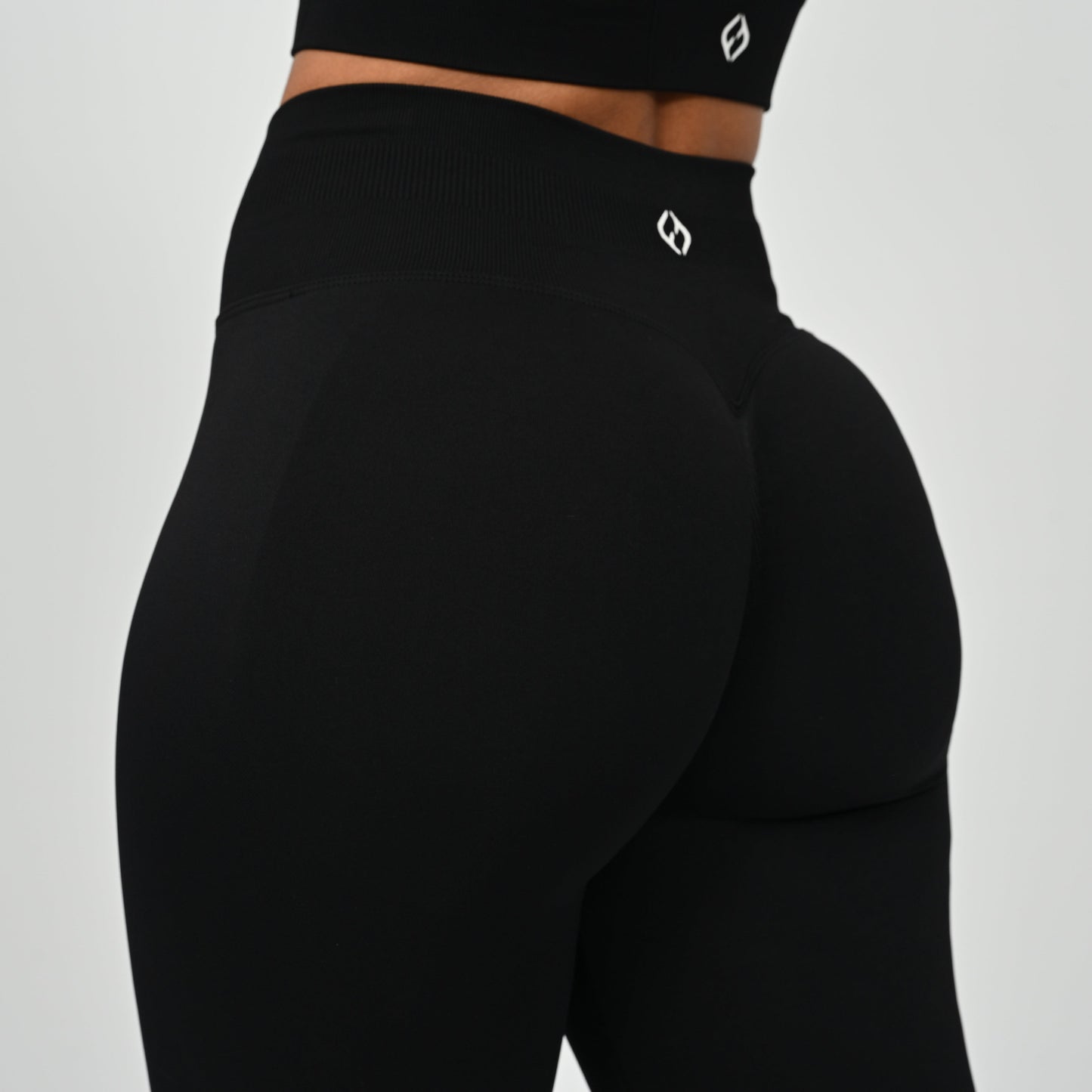 Crossfit athlete wearing plain black hybryd gym leggings. With a cinch bum and contouring. Part of the matching verona activewear set.