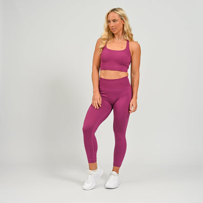 Hyrox gym girl wearing purple cinch bum leggings with contouring. Part of a matching set.  From gymwear brand Hybryd.