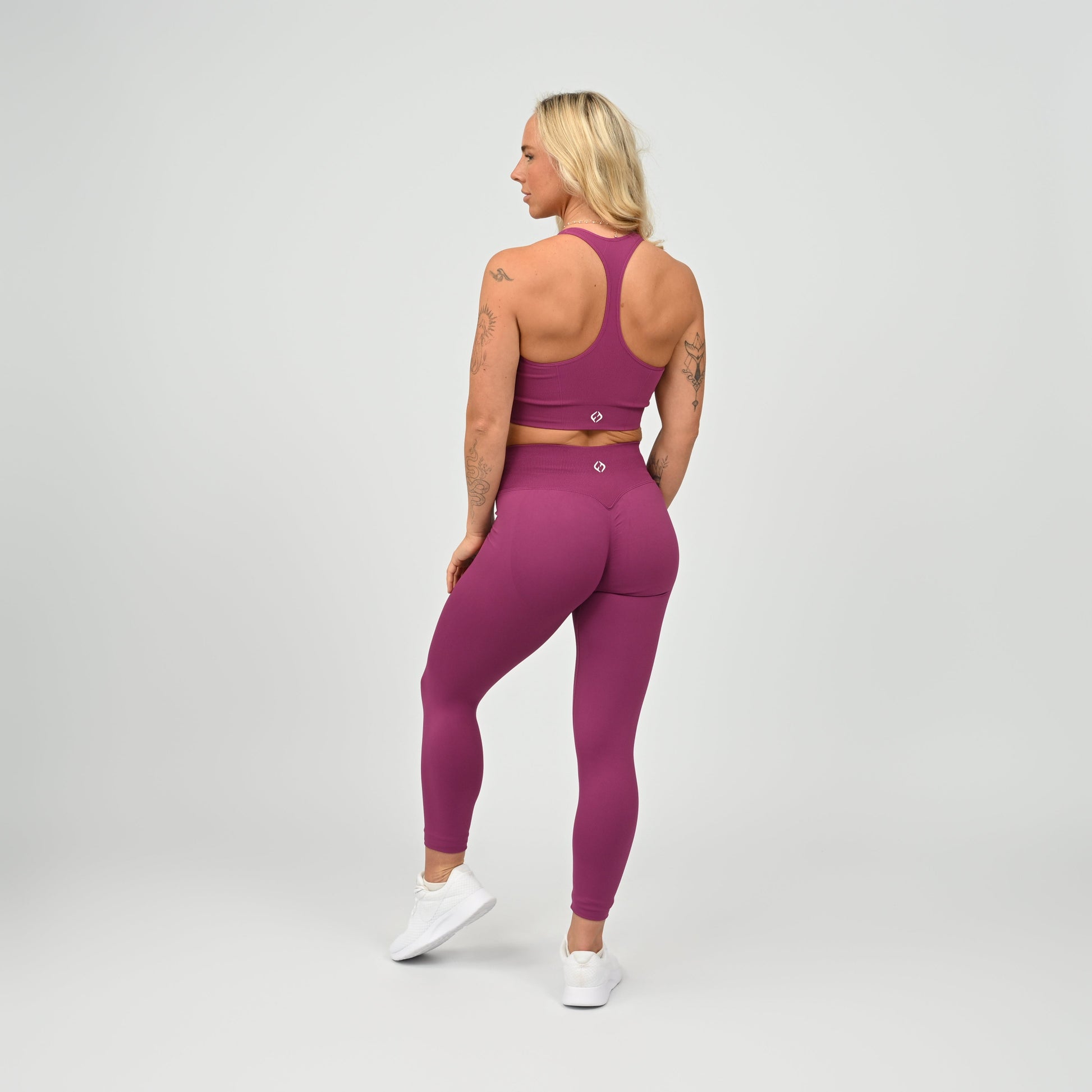 Hyrox gym girl wearing purple cinch bum leggings with contouring. Part of a matching set.  From gymwear brand Hybryd.