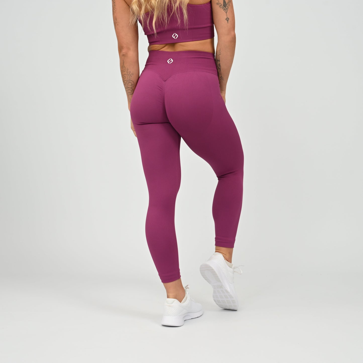 Hyrox gym girl wearing purple cinch bum leggings with contouring. Part of a matching set.  From gymwear brand Hybryd.