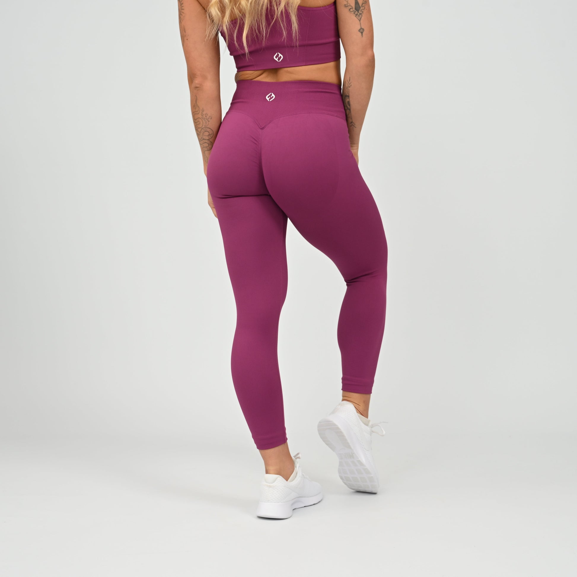 Hyrox gym girl wearing purple cinch bum leggings with contouring. Part of a matching set.  From gymwear brand Hybryd.
