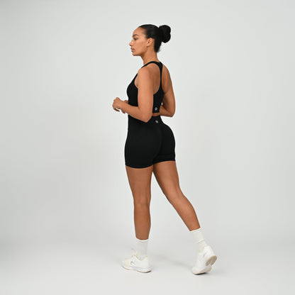Hyrox woman wearing black, high waisted, cinch bum workout bootie shorts with contouring. Teamed with a matching muscle back sports bra. From activewear brand Hybryd