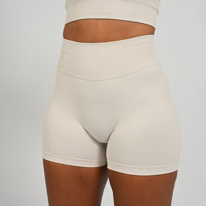 Hyrox woman wearing off white, high waisted, cinch bum workout bootie shorts with contouring. From activewear brand Hybryd