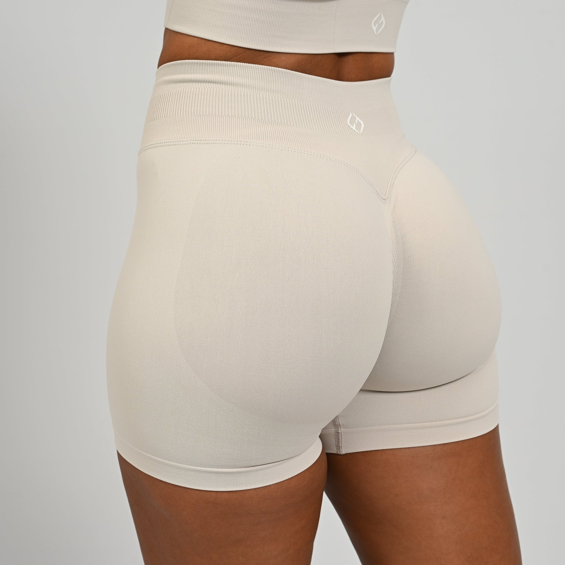 Hyrox woman wearing off white, high waisted, cinch bum workout bootie shorts with contouring. From activewear brand Hybryd