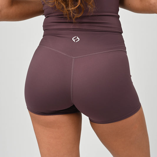 Person wearing maroon gym wear athletic shorts with a Hybryd logo on a light gray background