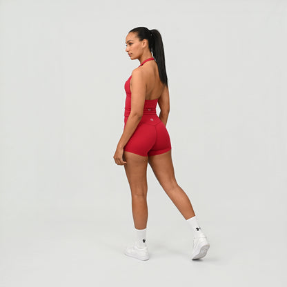 Woman wearing a red fitness wear matching set from Hybryd on a light grey background