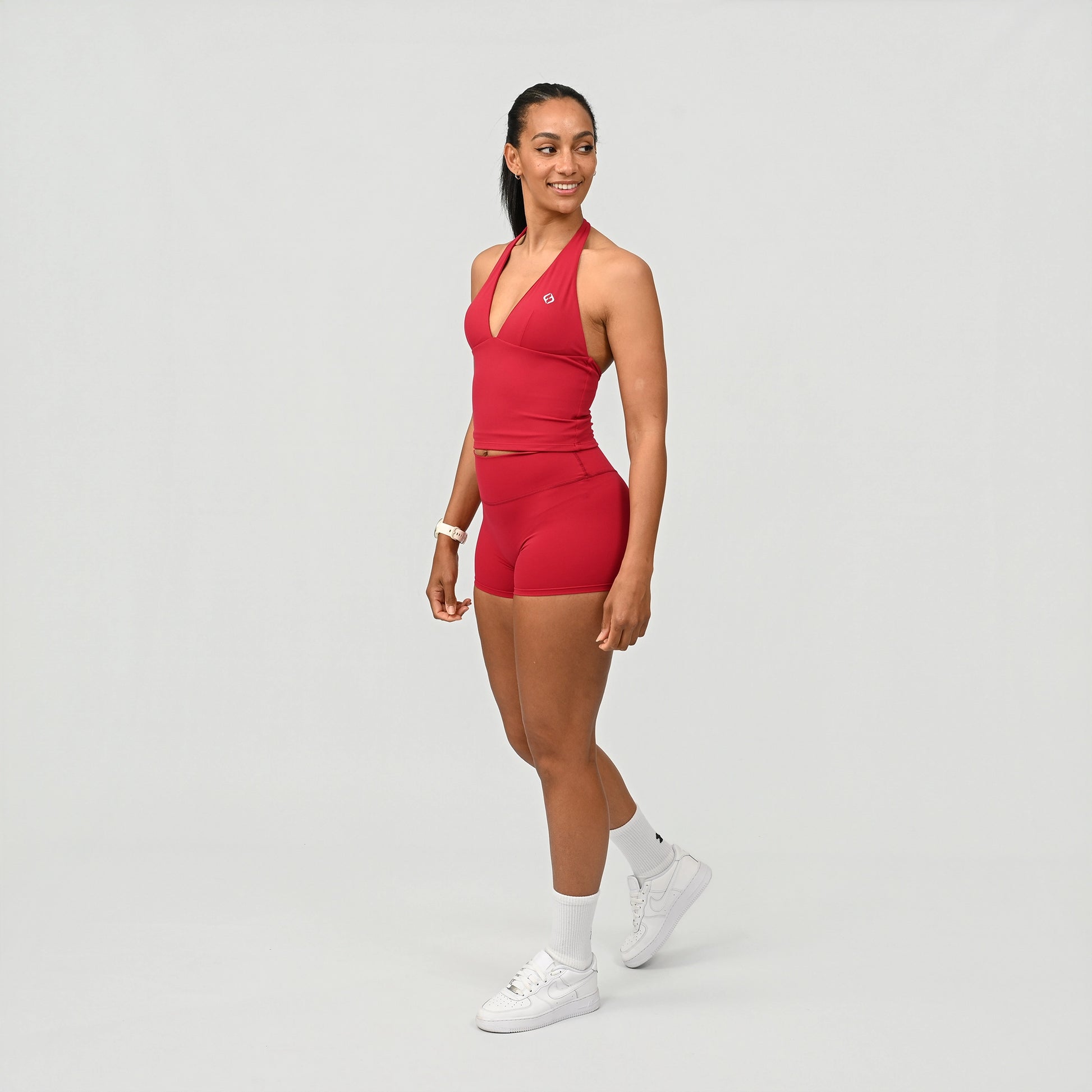 Woman wearing a red athletic Hybryd gym wear outfit on a light gray background