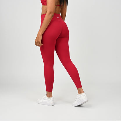 Person wearing red Hybryd leggings and white sneakers on a plain background