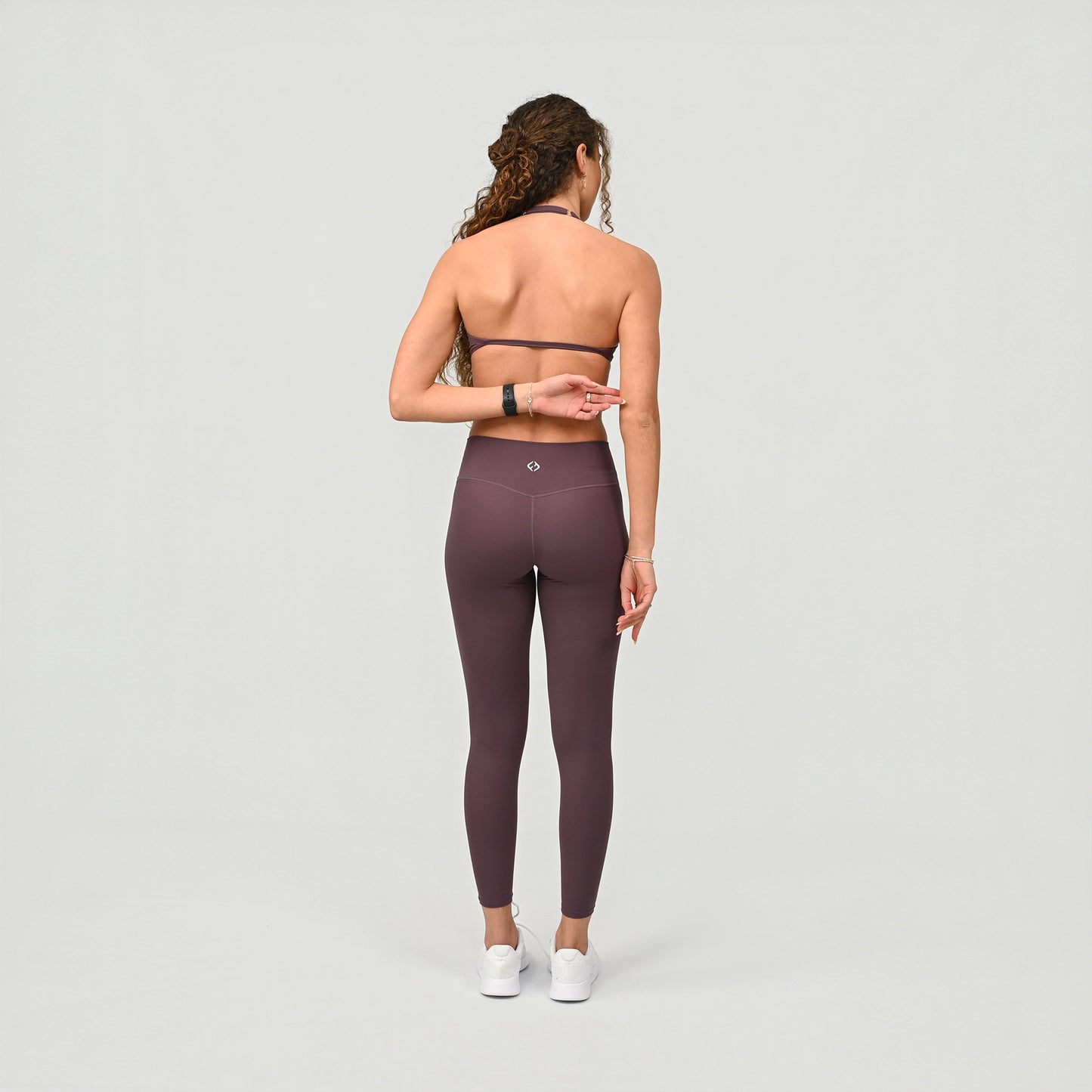 Person wearing high waist purple leggings on a light grey background from the gymwear brand Hybryd.