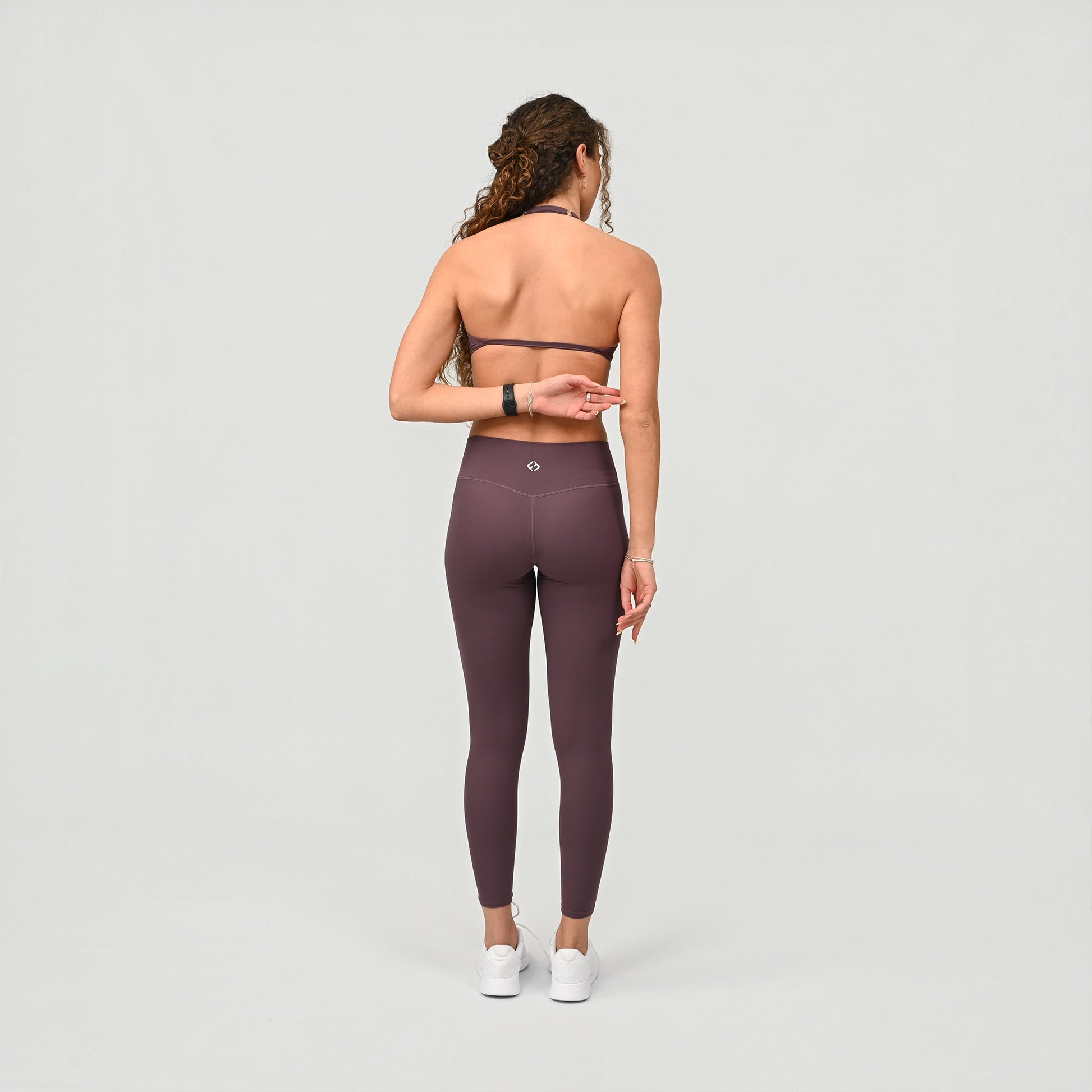 Person wearing high waist purple leggings on a light grey background from the gymwear brand Hybryd.