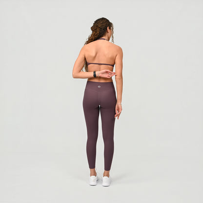 Person wearing high waist purple leggings on a light grey background from the gymwear brand Hybryd.