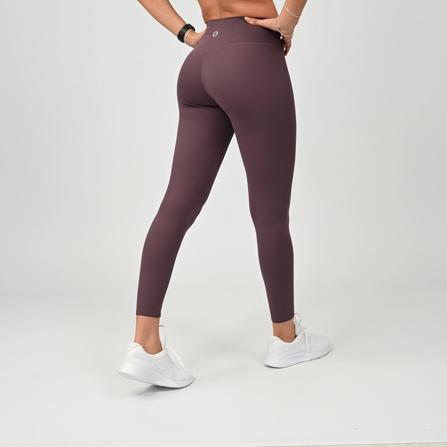 Person wearing kalamata gym leggings and white sneakers on a light gray background
