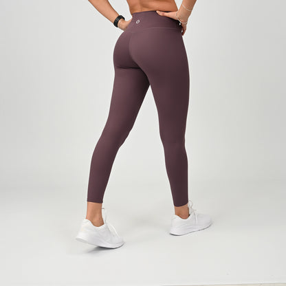 Person wearing kalamata gym leggings and white sneakers on a light gray background
