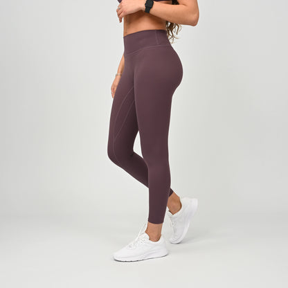 Person wearing soft maroon gym leggings and white sneakers on a light gray background