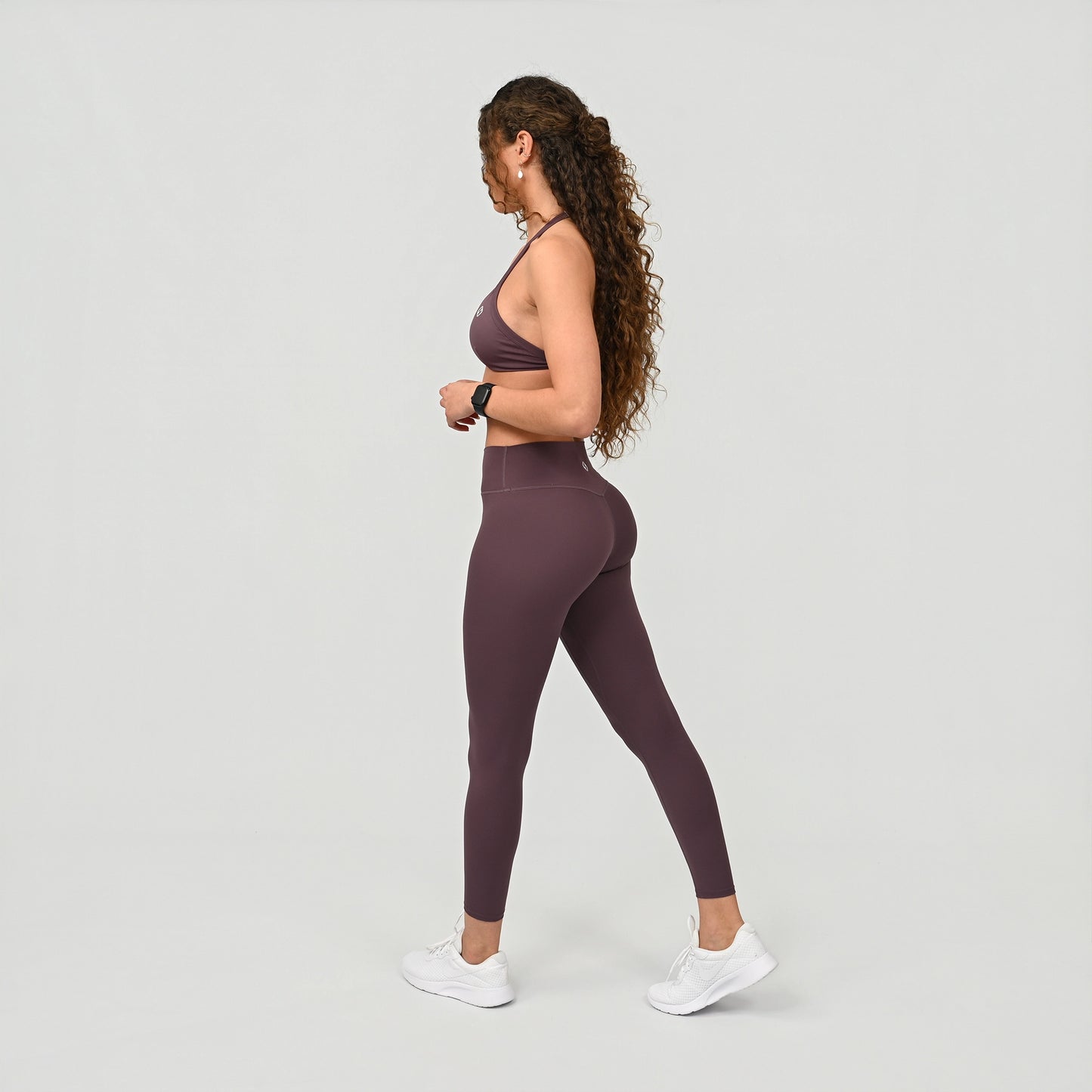 Woman wearing a purple buttery soft athletic outfit on a light gray background