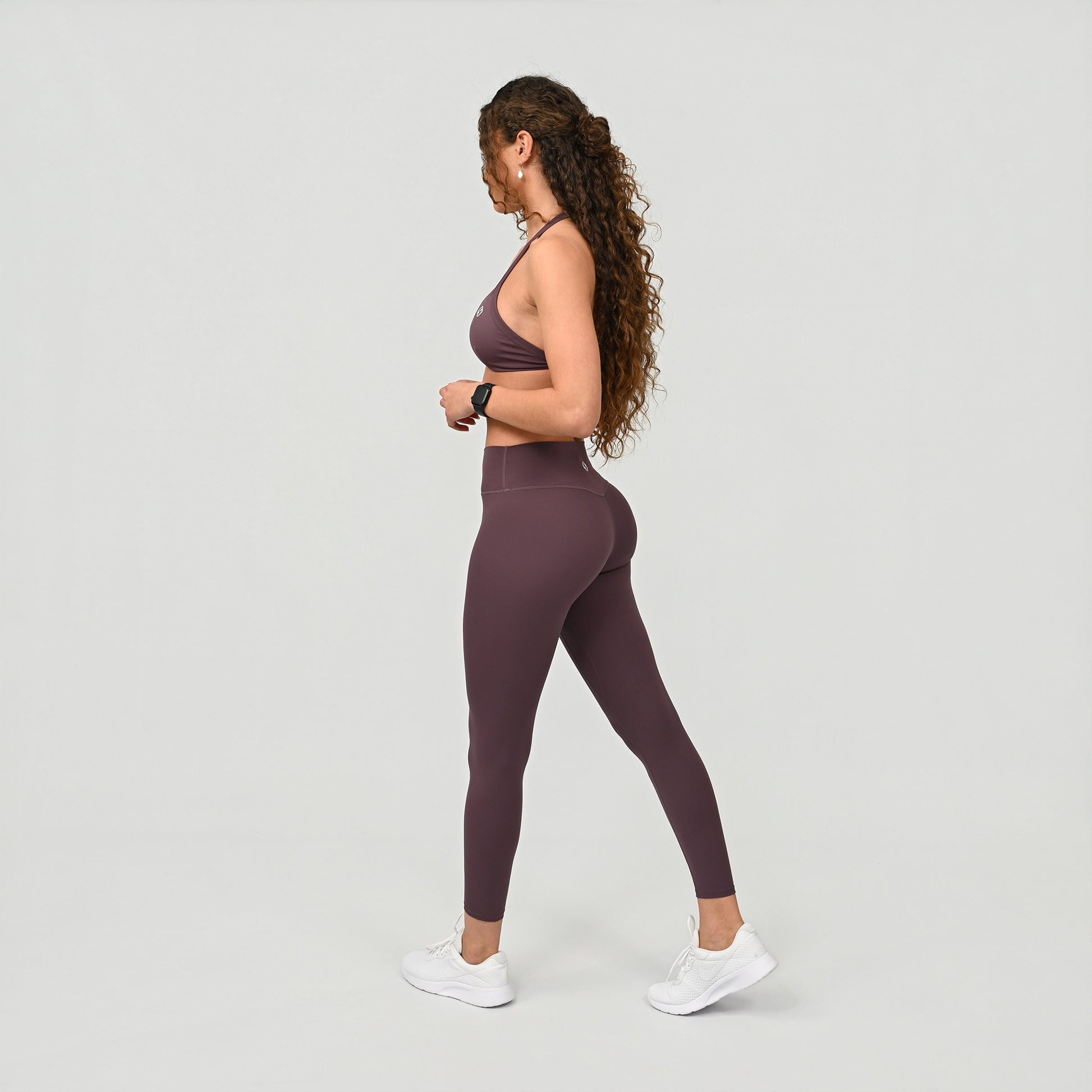 Woman wearing a purple buttery soft athletic outfit on a light gray background