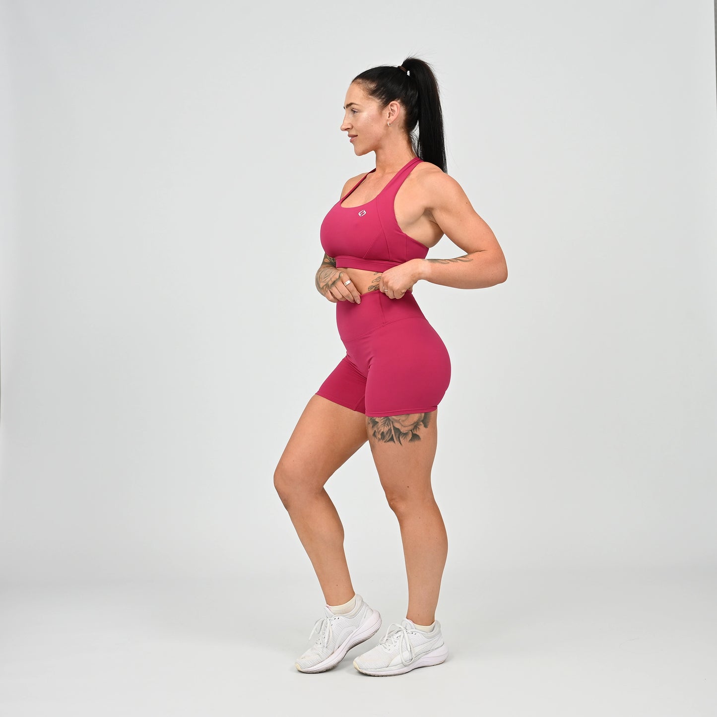 Hyrox girl wearing a raspberry coloured sports bra and cinch bum short. From activewear brand Hybryd.