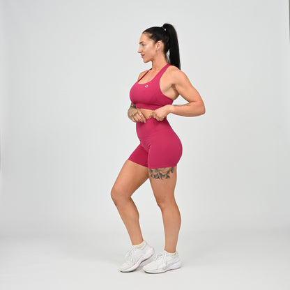 Hyrox girl wearing a raspberry coloured sports bra and cinch bum short. From activewear brand Hybryd.