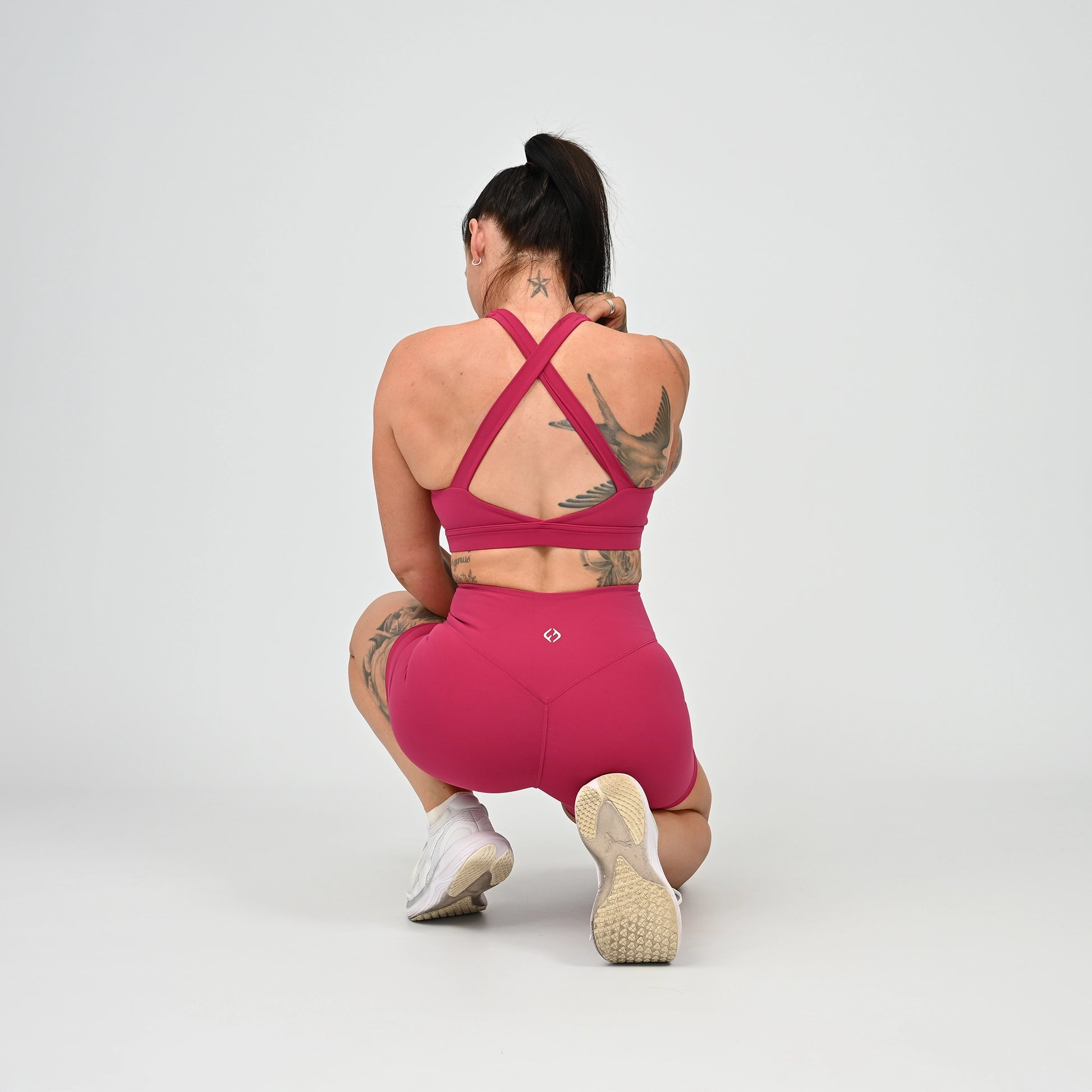 Hyrox girl wearing a raspberry coloured sports bra and cinch bum short. From activewear brand Hybryd.