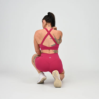 Hyrox girl wearing a raspberry coloured sports bra and cinch bum short. From activewear brand Hybryd.