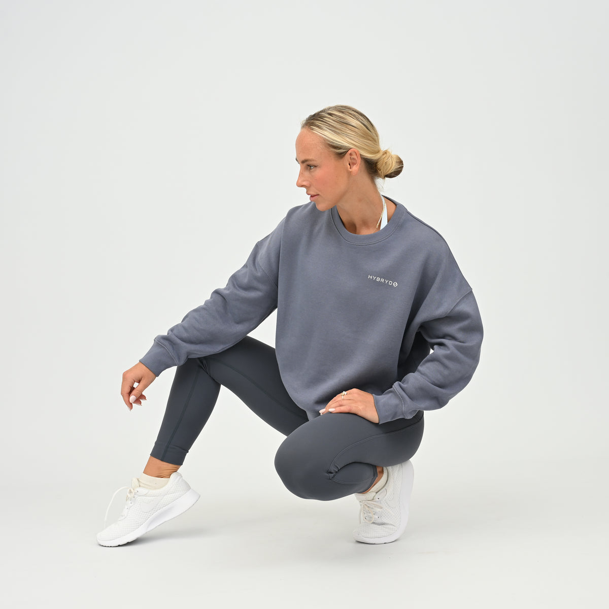 Women’s HYBRYD oversized organic cotton sweatshirt in washed slate grey, with chest logo, styled with dark grey gym leggings.