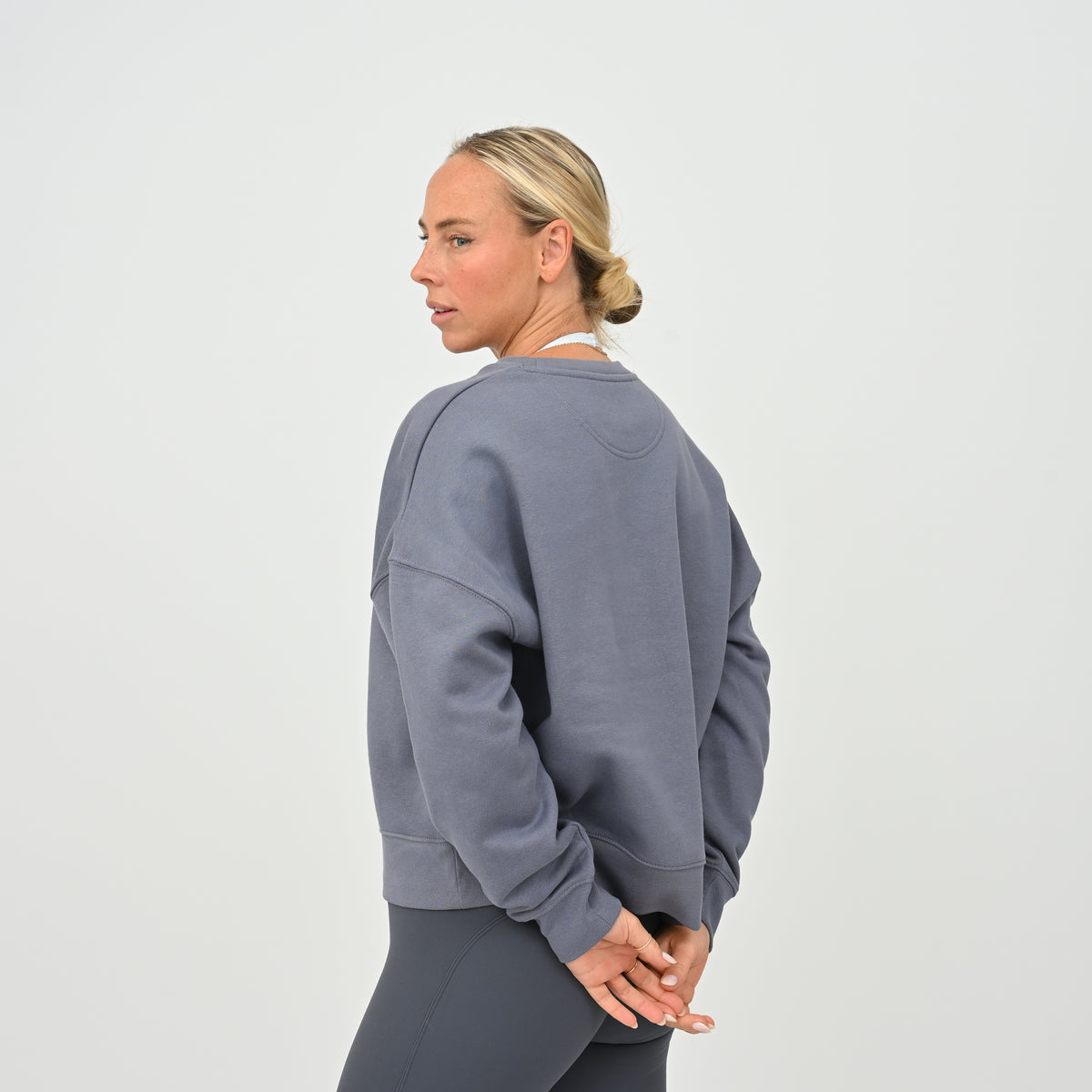 Women’s HYBRYD oversized organic cotton sweatshirt in washed slate grey, with chest logo, styled with dark grey gym leggings.
