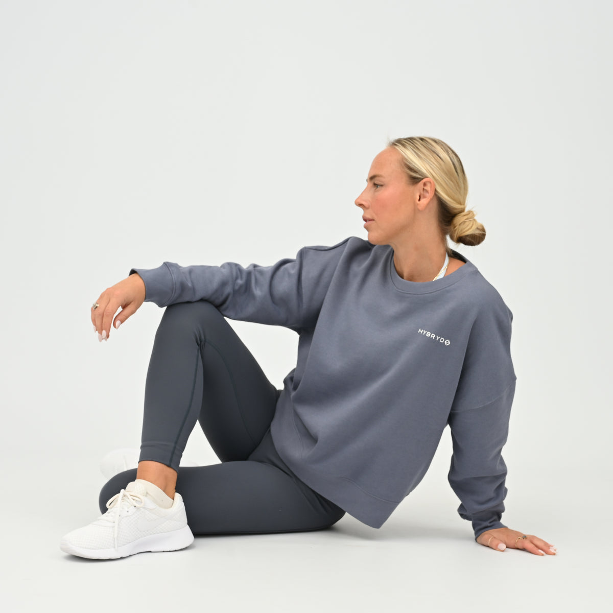 Women’s HYBRYD oversized organic cotton sweatshirt in washed slate grey, with chest logo, styled with dark grey gym leggings.