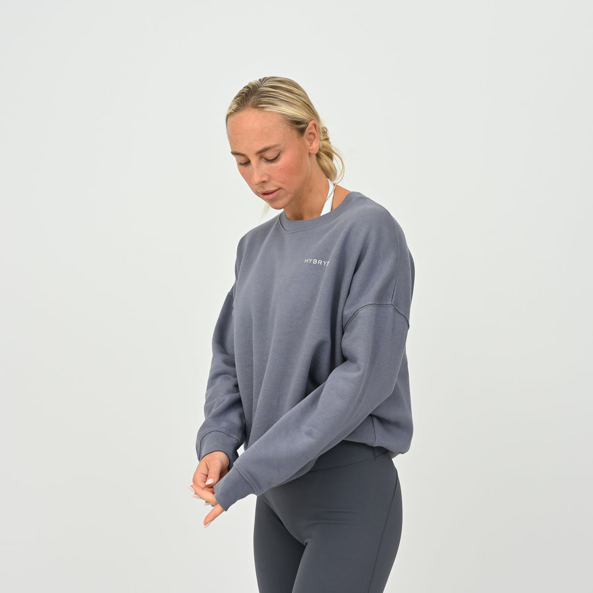 Women’s HYBRYD oversized organic cotton sweatshirt in washed slate grey, with chest logo, styled with dark grey gym leggings.