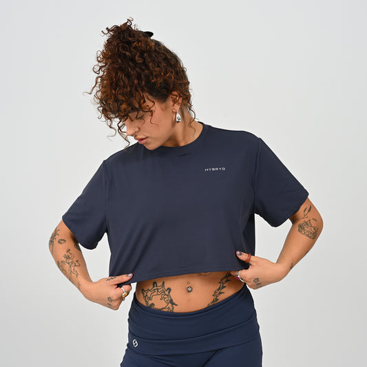 A training tee, oversized, cropped fit in Navy colour. HYBRYD branding on upper left chest. Worn by a gym girl. From activewear brand Hybryd.