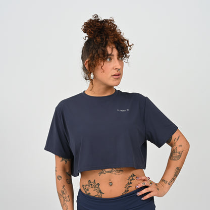 A training tee, oversized, cropped fit in Navy colour. HYBRYD branding on upper left chest. Worn by a gym girl. From activewear brand Hybryd.