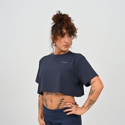 A training tee, oversized, cropped fit in Navy colour. HYBRYD branding on upper left chest. Worn by a gym girl. From activewear brand Hybryd.