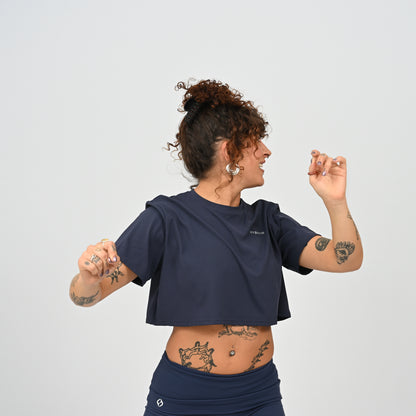 A training tee, oversized, cropped fit in Navy colour. HYBRYD branding on upper left chest. Worn by a gym girl. From activewear brand Hybryd.