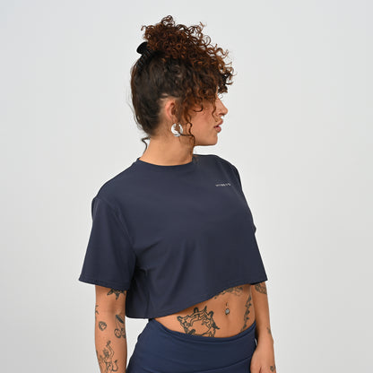 A training tee, oversized, cropped fit in Navy colour. HYBRYD branding on upper left chest. Worn by a gym girl. From activewear brand Hybryd.