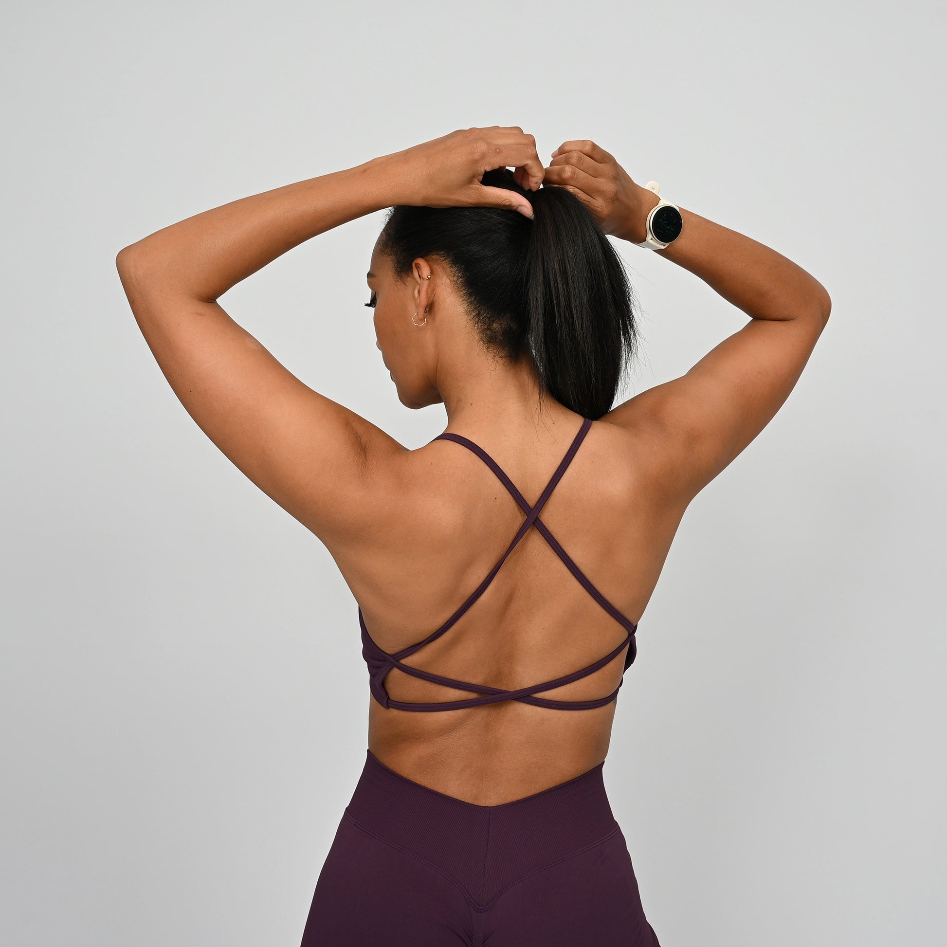 Woman wearing a purple Hybryd sports bra and matching leggings with a rear v-dip and scrunch bum.